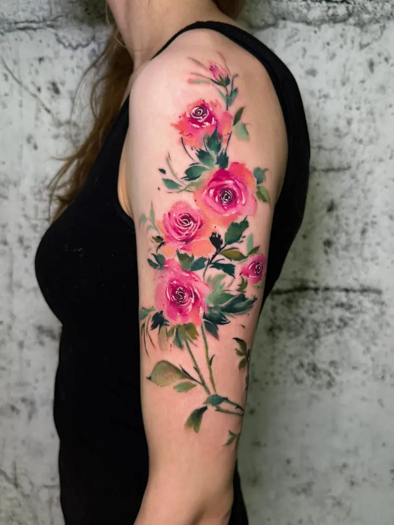 Aquarell-Rosen in Pink und Grün über den Oberarm, tätowiert von Maya in Frankfurt.