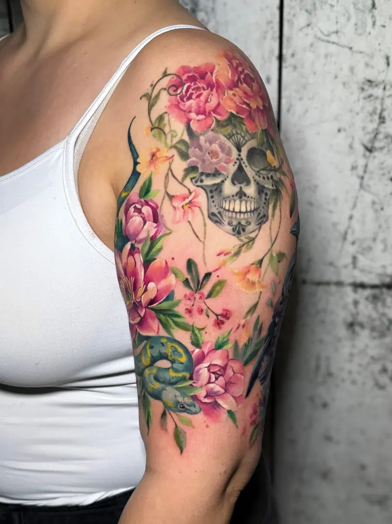 Watercolor-Sleeve mit Totenkopf und Pfingstrosen am Oberarm, tätowiert von Maya.
